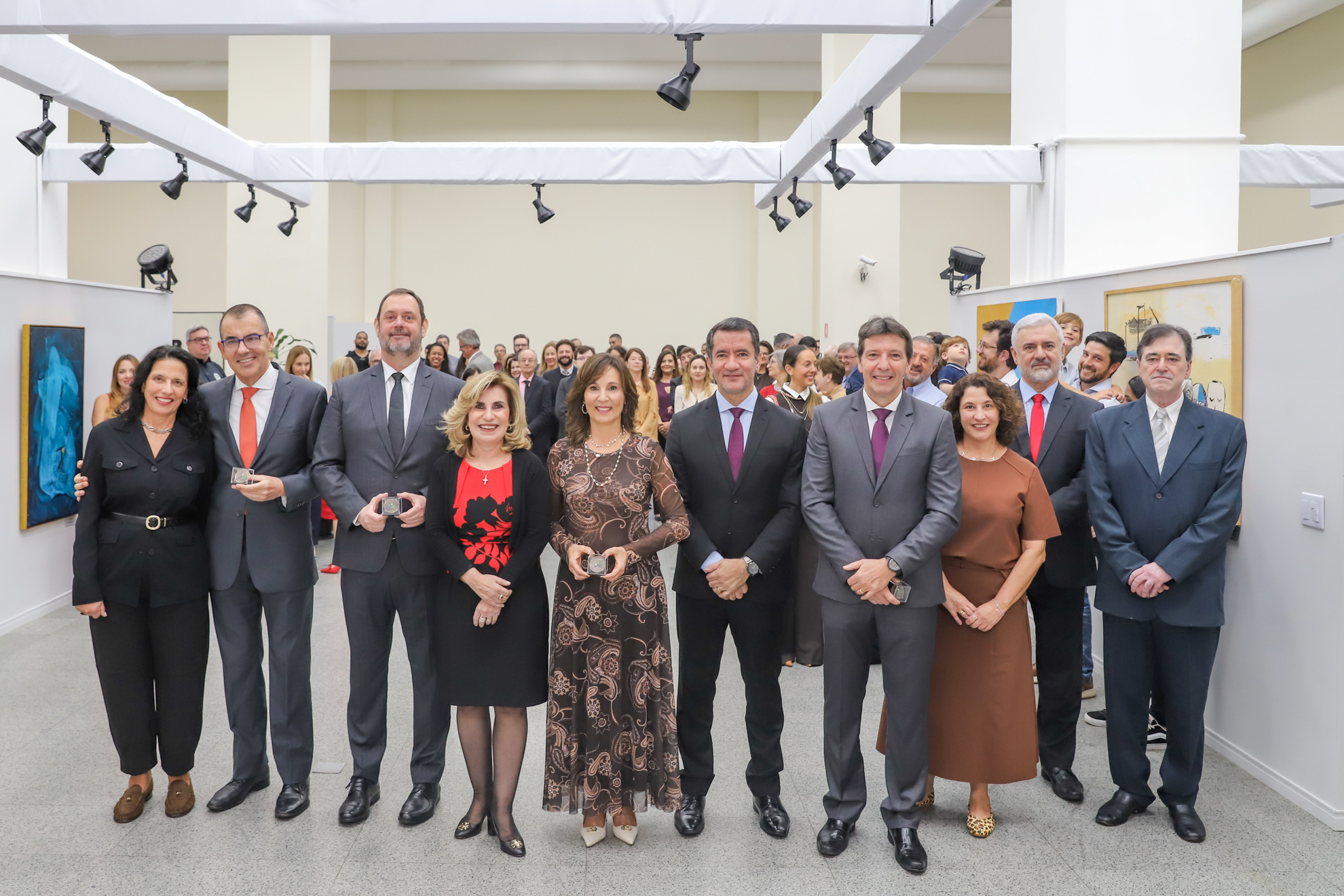 Os homenageados posam para a foto em pé, atrás o público que acompanhou o evento.