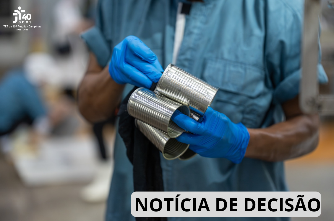 Uma mão de trabalhador segura uma emabalhar metálica dentro de uma fábrica.